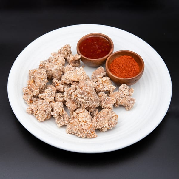 Hiccups' crispy popcorn chicken with a side of sweet chili sauce and chili powder.
