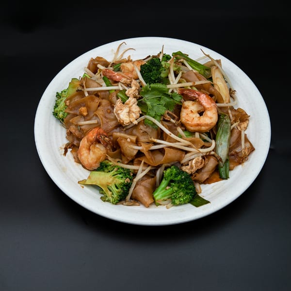Hiccups' Asian-fusion dish with flat noodles, shrimp, broccoli, bean sprouts, and cilantro on a white plate.