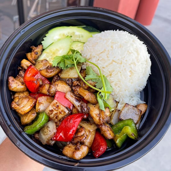 Hiccups' Asian-fusion dish with chicken, red and green bell peppers, onions, white rice, and cucumber slices.