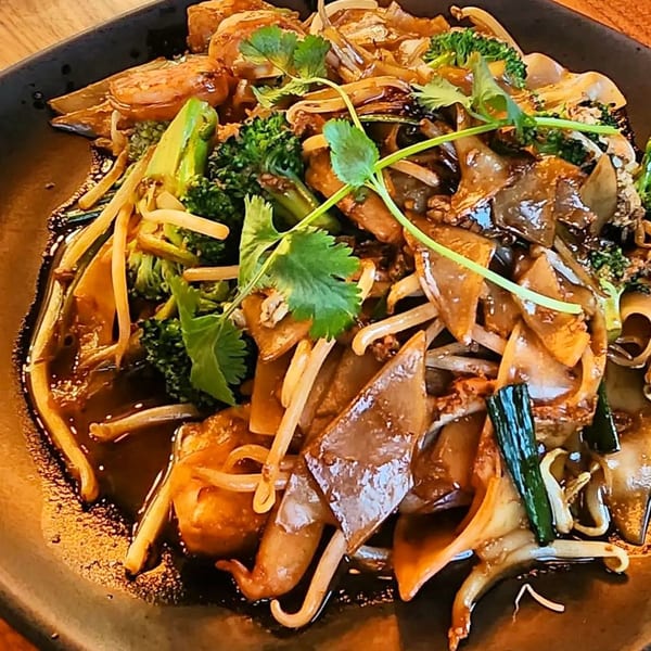 Hiccups' Asian-fusion dish with wide noodles, broccoli, bean sprouts, and cilantro in a dark sauce.